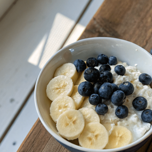 Bowl of cottage cheese topped with sliced bananas and fresh blueberries