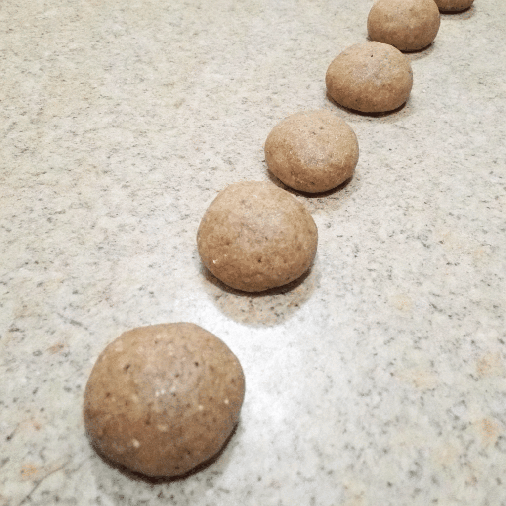 Row of sourdough crispbread dough balls resting on a countertop.