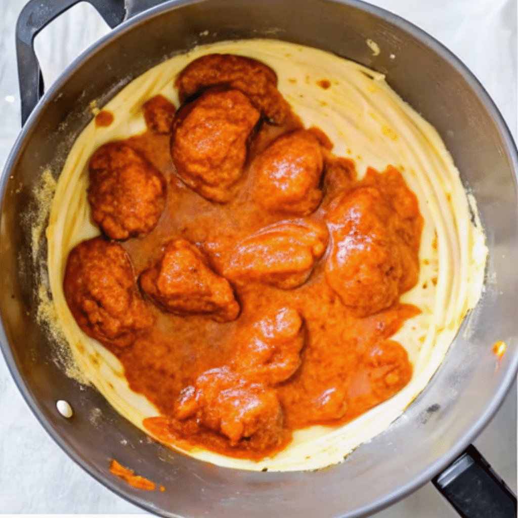 Butter chicken simmering in creamy tomato sauce in a black cooking pot